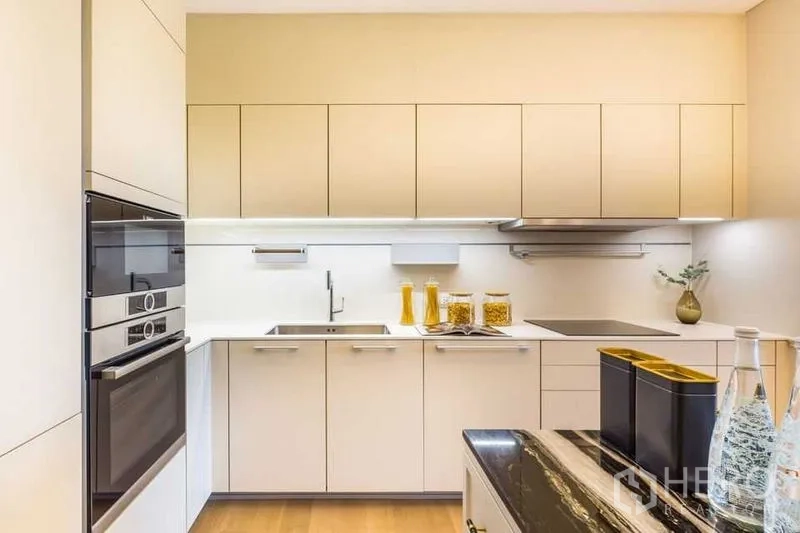 Condominium for rent in Pathum Wan, Bangkok - Fully fitted kitchen with integrated ovens, induction hob, and ample cabinetry.