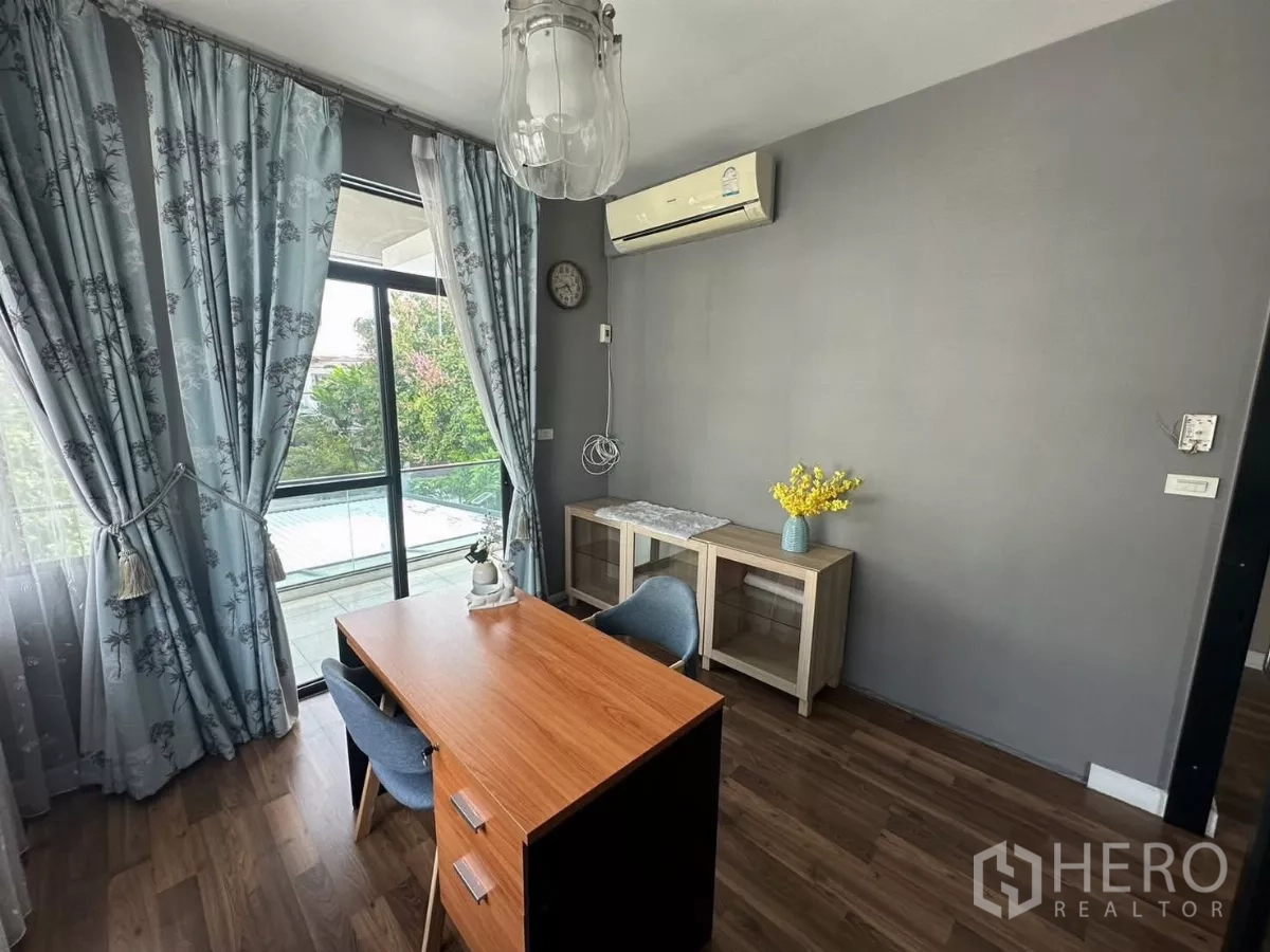 Detached House for rent or sale in Bang Kapi, Bangkok - Home office with desk, blue curtains and access to a glass balcony.