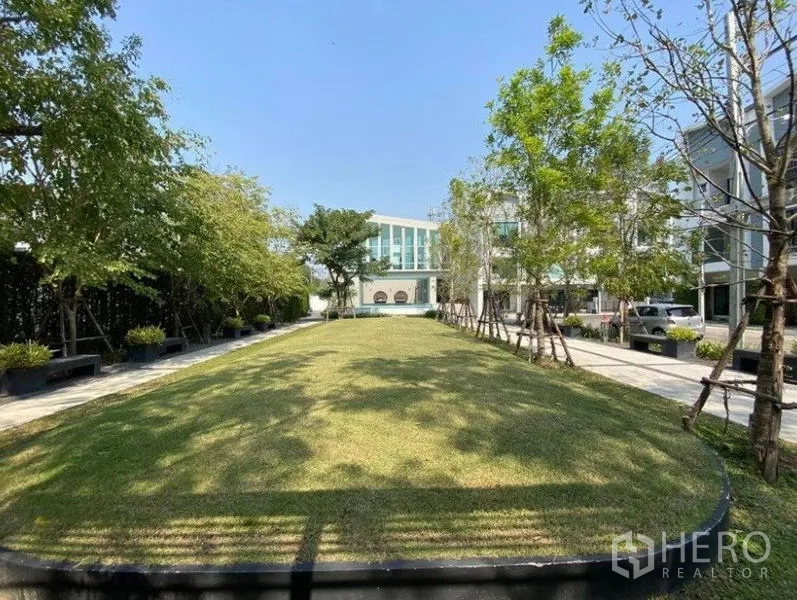 Townhouse for rent in Bang Na, Bangkok - Landscaped communal garden with lawn, trees and seating within the estate.