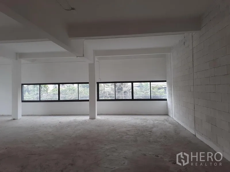 办公空间 出租在Khlong Toei, Bangkok - Phra Khanong开放式办公室室内，长条横向窗、白色砖墙与外露梁，采光充足。