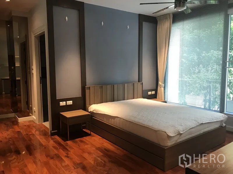 房间 出租在Pathum Wan, Bangkok - 大卧室，蓝色特色墙、吊扇与整面窗户百叶