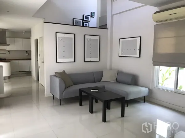 Detached House for rent or sale in Saphan Sung, Bangkok - Bright living room with grey L-shaped sofa, glossy tile floors and open-plan layout.