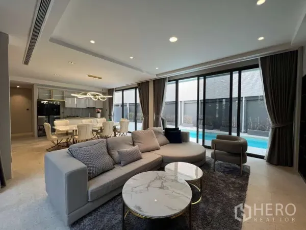Detached House for rent in Suan Luang, Bangkok - Open‑plan living and dining with large sofa and sliding glass doors to a private pool.