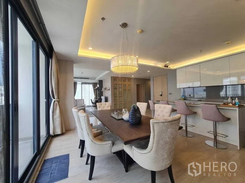 Condominium for sale - Elegant dining area with chandelier beside a breakfast bar and glossy kitchen cabinets.