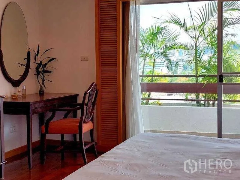 Apartment for rent - Bedroom corner with dressing table and sliding door to a balcony with plants.