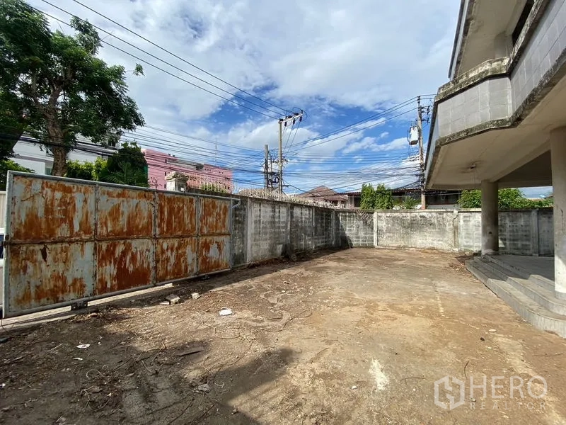 สำนักงาน ขายในWang Thonglang, Bangkok - ลานด้านหน้าพร้อมประตูเหล็กบานเลื่อนเป็นสนิม และกำแพงรอบที่ดิน