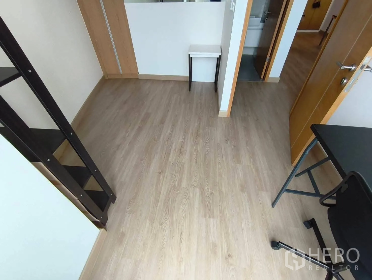 Condominium for rent in Khlong Toei, Bangkok - Second bedroom or study with wood floors, desk and chair, ladder shelf, and doorway to a bathroom.