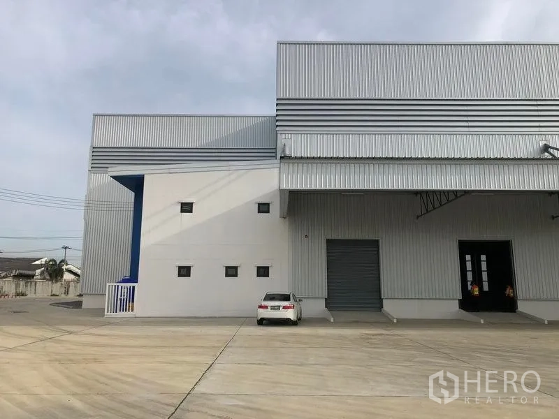 Factory for rent in Samut Prakan - Loading bay zone with roller shutter door, canopy roof and large concrete yard for truck access.