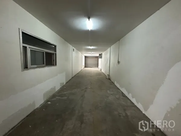 Warehouse for rent in Suan Luang, Bangkok - Long internal corridor leading to a rear roller door and service area.