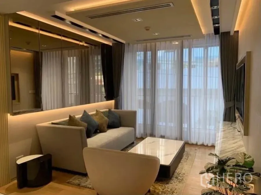 公寓 出租在Watthana, Bangkok - 现代客厅，沙发、落地纱帘、暖色灯光与大理石电视墙。