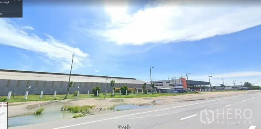 货栈 出租在Mueang Chon Buri, Chon Buri - 春武里直辖县宽阔马路旁的大型工业仓库外观，晴空背景。