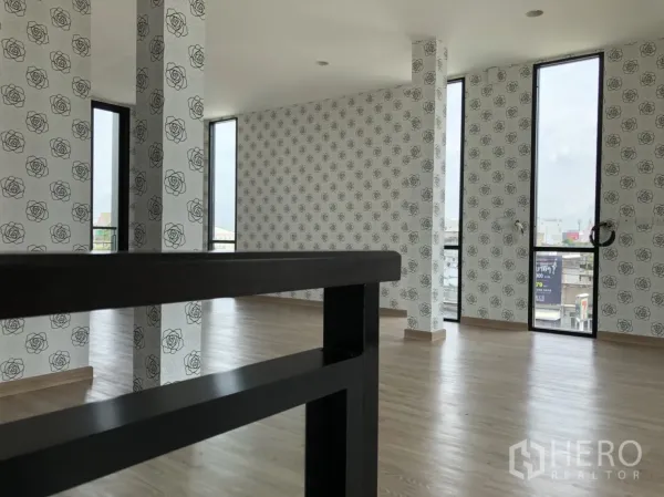 Townhouse for rent in Din Daeng, Bangkok - Upper-floor room with rose-pattern wallpaper, tall narrow windows, and wood flooring.