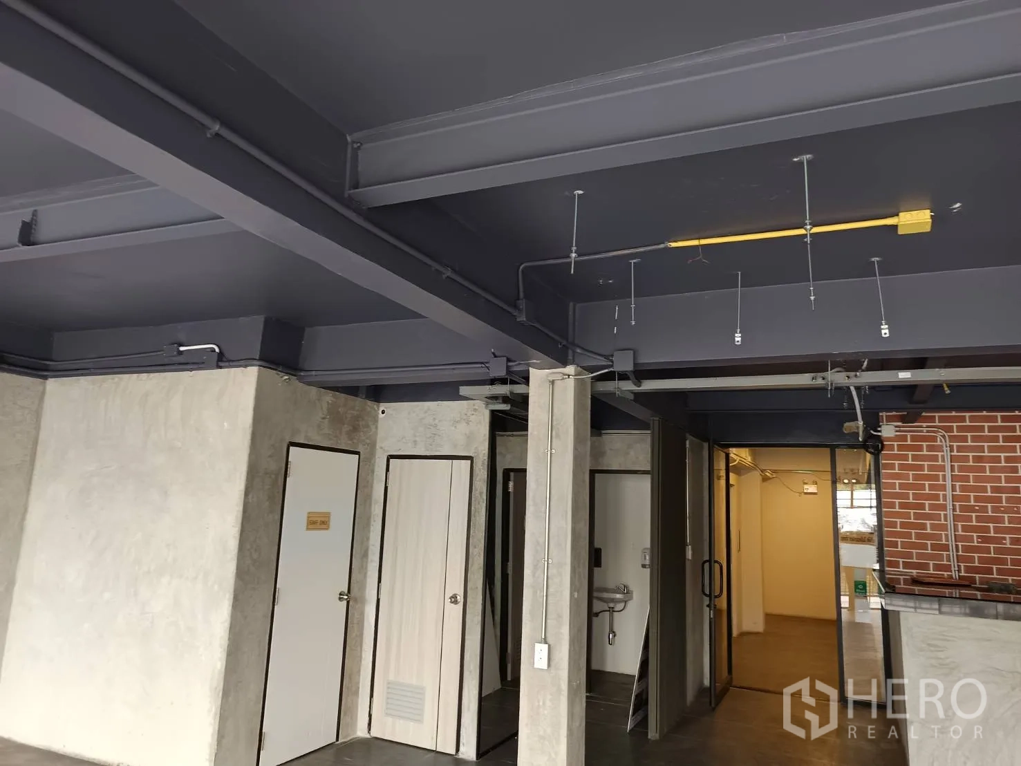 Retail Space for rent in Watthana, Bangkok - Exposed ceiling detail with conduits above doors and a glass entry near the counter.