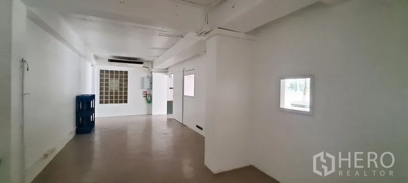 Retail Space for rent in Bang Rak, Bangkok - Back-of-house corridor with white walls, glass-block window, electrical panel and storage rooms.