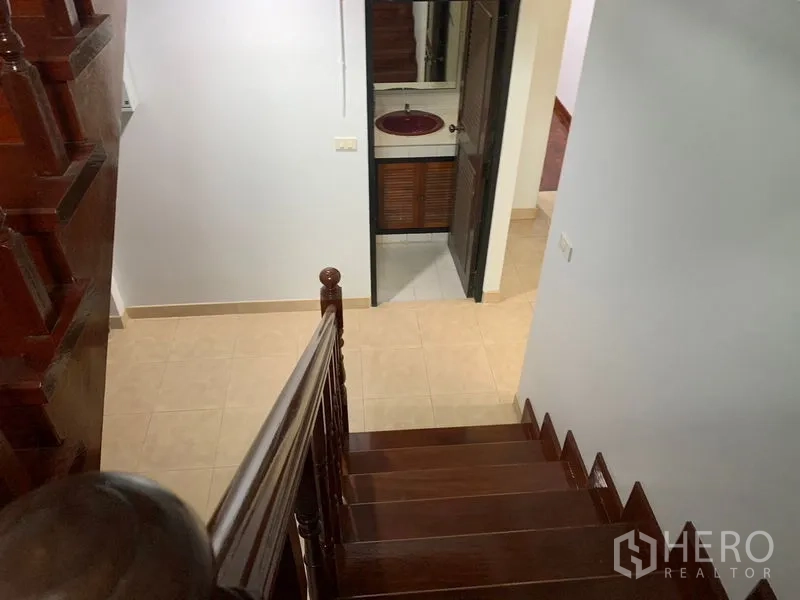 Detached House for rent in Khlong Toei, Bangkok - Wooden staircase and landing leading to a bathroom with vanity.