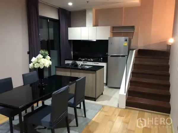 公寓 出租或出售在Khlong San, Bangkok - 开放式厨房带岛台，不锈钢冰箱与玻璃扶手楼梯，旁接餐区。