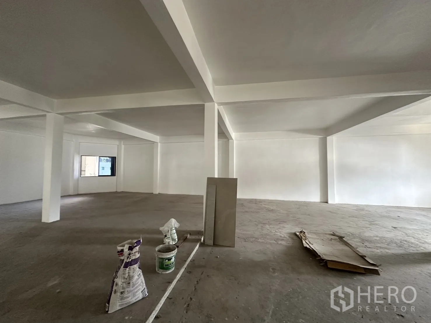 Retail Space for rent in Watthana, Bangkok - Large unfinished retail interior with support columns, concrete floor, and a single window.