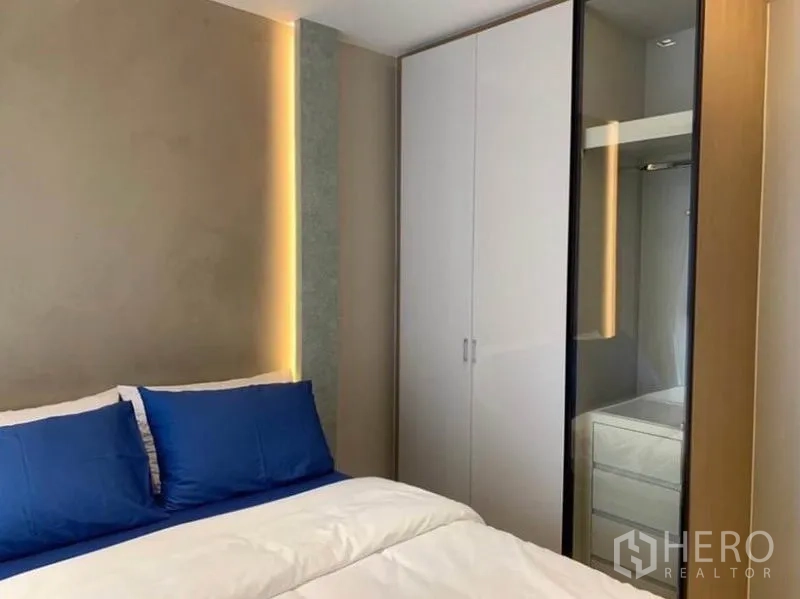 公寓 出租在Watthana, Bangkok - 次卧衣柜，白色柜体带玻璃门与照明。