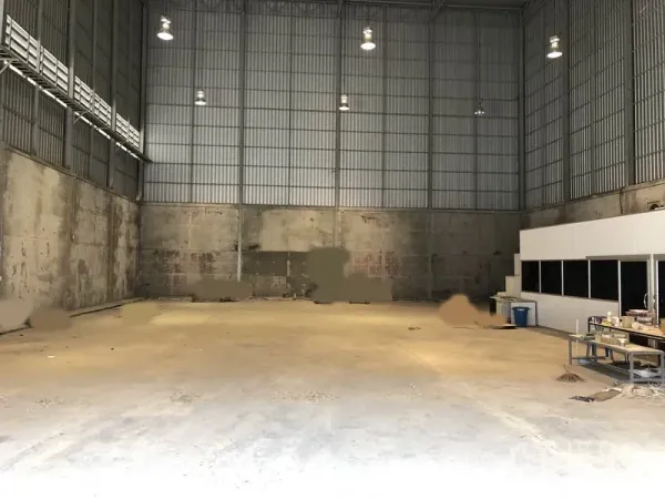 Warehouse for rent in Lam Luk Ka, Pathum Thani - Open concrete storage floor with tall walls and overhead lighting providing clear-span space.
