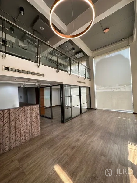 办公空间 出租在Pathum Wan, Bangkok - 宽敞双层挑高办公室，设夹层、玻璃隔断与现代圆环吊灯。