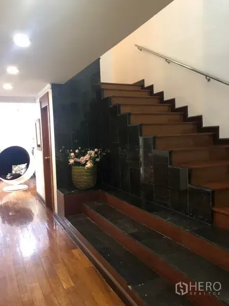 Condominium for sale - Interior staircase with wood steps and dark stone accents beside a lit hallway.