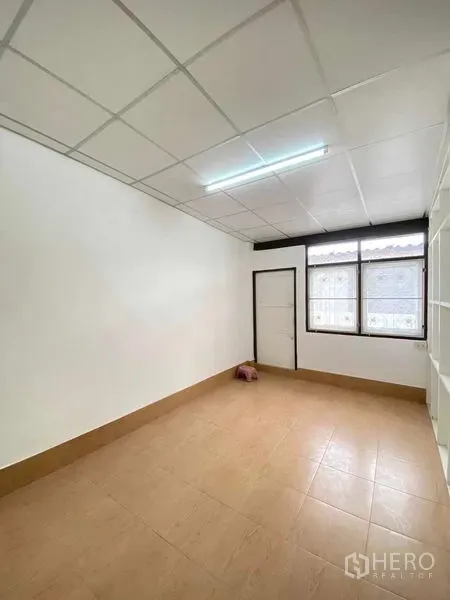 Shophouse for sale in Phra Khanong, Bangkok - Compact room with tiled floor, drop ceiling and a window bringing light into the shophouse.