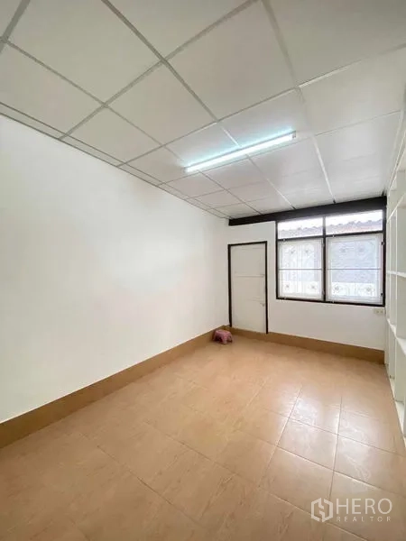 Shophouse for sale in Phra Khanong, Bangkok - Compact room with tiled floor, drop ceiling and a window bringing light into the shophouse.