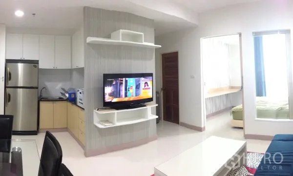 公寓 出租在Phaya Thai, Bangkok - 开放式客厅，墙面电视、L形厨房与卧室门，采光良好。