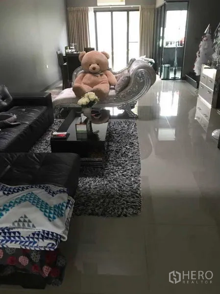 Townhouse for rent - Open-plan living room with leather sofa, shag rug, glass coffee table, and sliding doors to a balcony.