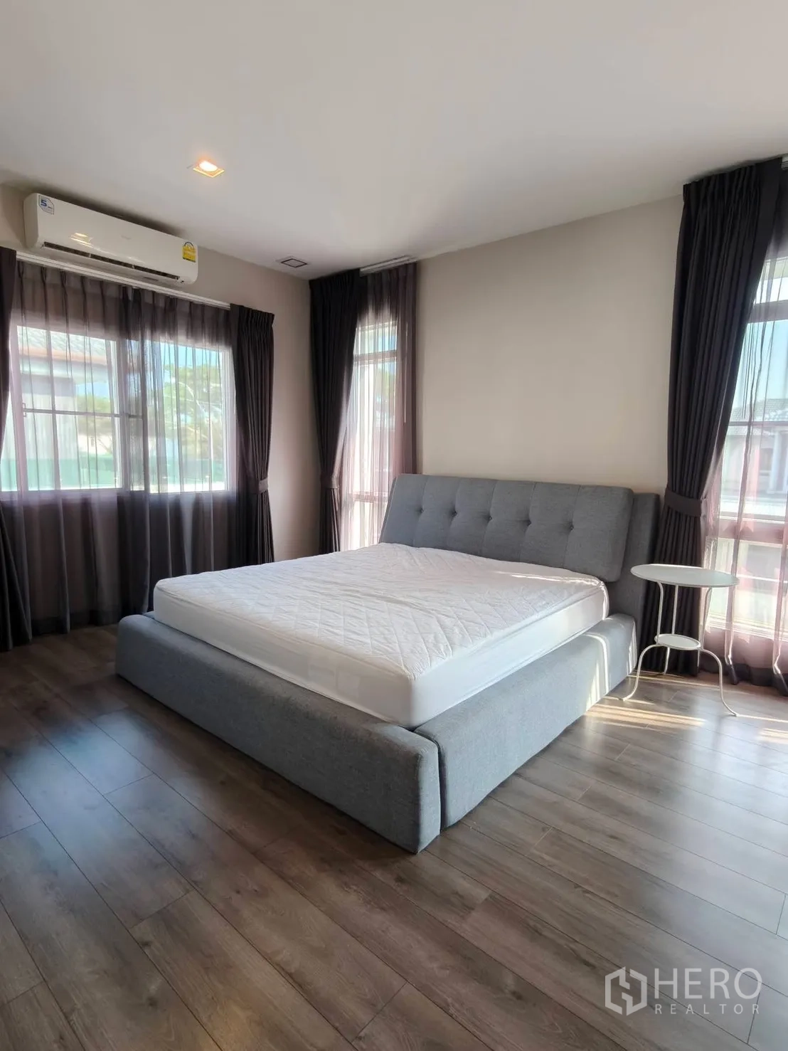บ้านเดี่ยว for rent or sale in Bang Phli, Samut Prakan - ห้องนอนมุมบ้านพร้อมหน้าต่างบานใหญ่ ผ้าม่านทึบ และพื้นไม้.