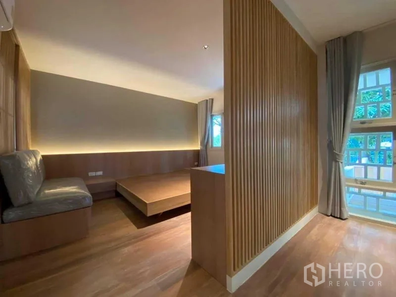 Detached House for rent in Watthana, Bangkok - Minimalist bedroom with platform bed and wood accents.