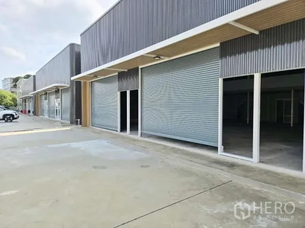 Warehouse for rent in Wang Thonglang, Bangkok - Row of modern warehouse units in Wang Thonglang with roller shutter doors and a wide driveway.