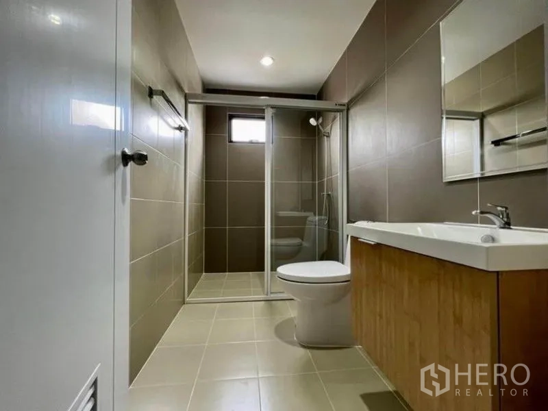 联排别墅 出租在Wang Thonglang, Bangkok - 现代浴室，玻璃淋浴间、盥洗台与坐便。