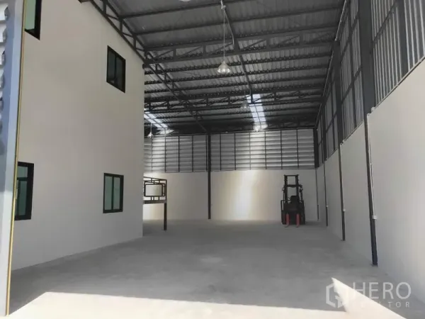 工厂 出租在Lam Luk Ka, Pathum Thani - 高挑仓库地面，吊灯照明，办公室旁留有叉车作业区。