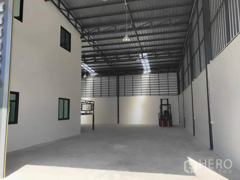 工厂 出租在Lam Luk Ka, Pathum Thani - 高挑仓库地面，吊灯照明，办公室旁留有叉车作业区。