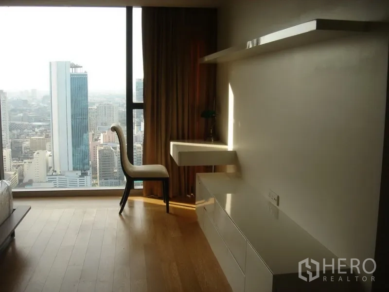 Condominium for rent in Sathon, Bangkok - Bedroom corner with floor-to-ceiling window, skyline views, floating desk and shelves.