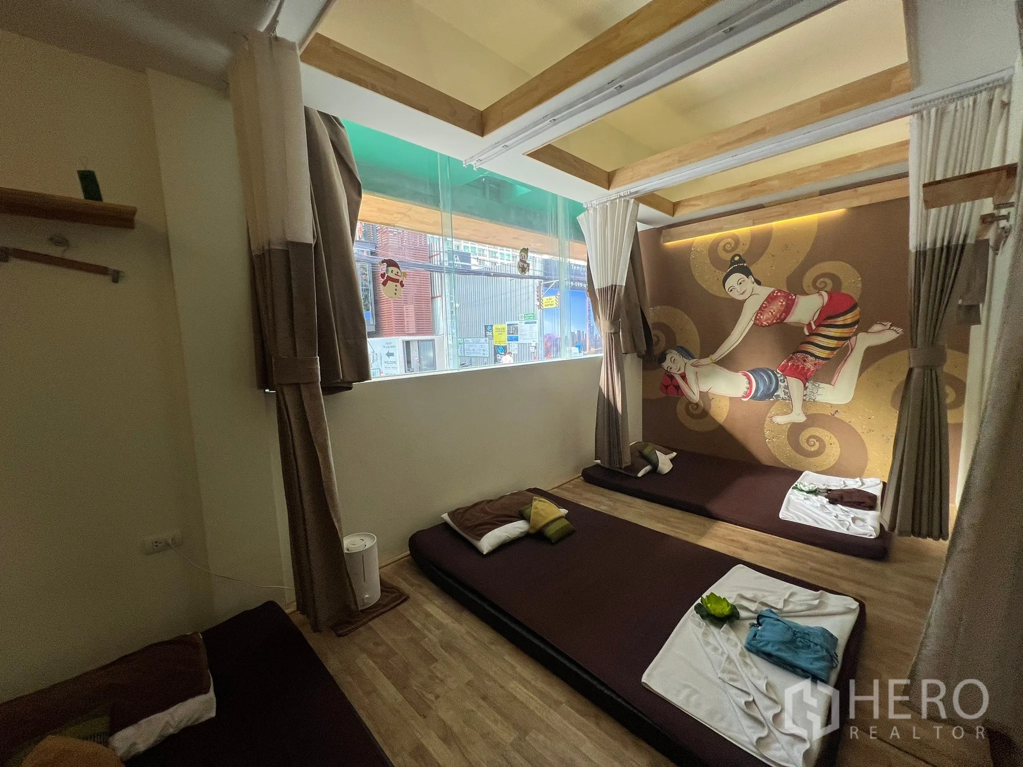 Retail Space for rent in Khlong Toei, Bangkok - Group room with floor mattresses, curtains, wood ceiling beams and a large window.