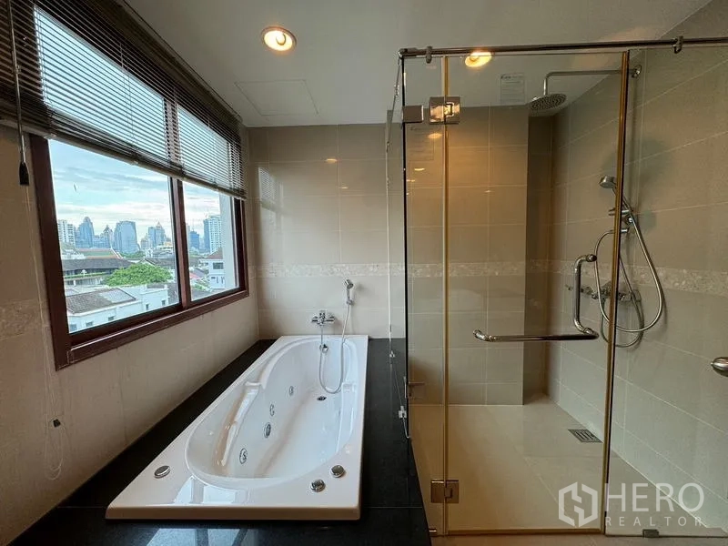 Condominium for rent in Pathum Wan, Bangkok - Luxury bathroom with glass shower, jetted bathtub, and window to skyline views.