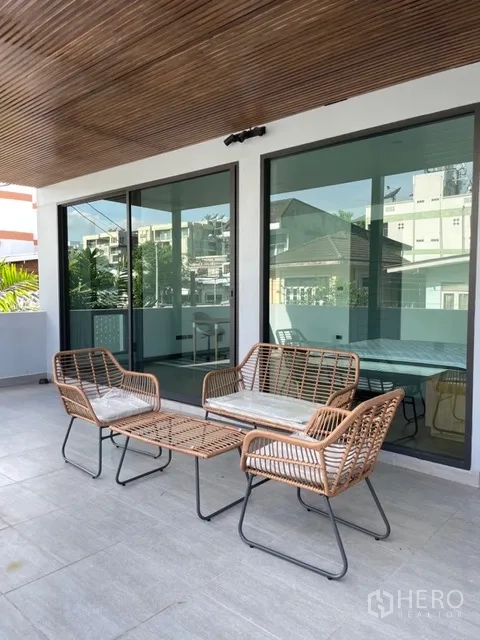 独栋房屋 for rent in Watthana, Bangkok - 覆顶露台，藤编户外沙发与推拉门。