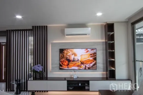 บ้าน ขายในSaphan Sung, Bangkok - ผนังทีวีบิวท์อินพร้อมไฟซ่อนและชั้นวาง ในห้องนั่งเล่นโมเดิร์น