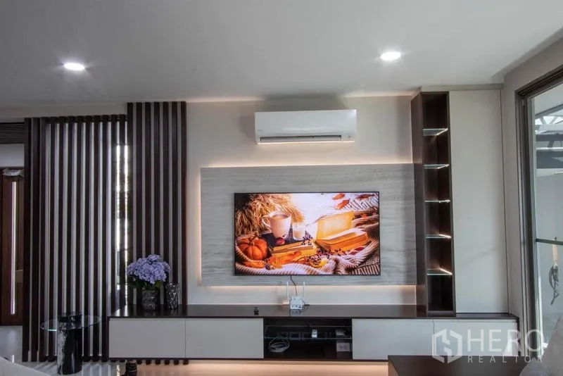 บ้าน ขายในSaphan Sung, Bangkok - ผนังทีวีบิวท์อินพร้อมไฟซ่อนและชั้นวาง ในห้องนั่งเล่นโมเดิร์น