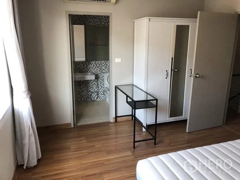 Townhouse for rent in Yan Nawa, Bangkok - Bedroom with en-suite door, white wardrobe and wood floors.