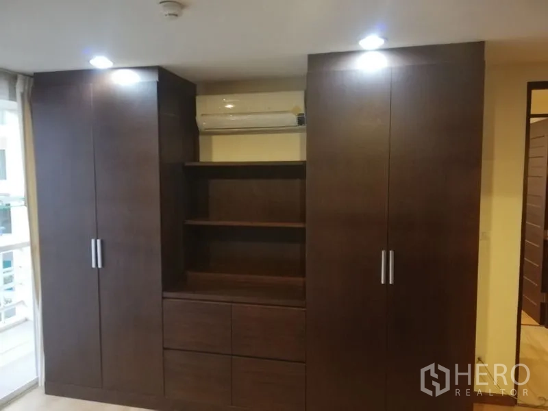 公寓 出租在Watthana, Bangkok - 深色木质嵌入式衣柜与层架，上方为空调内机。