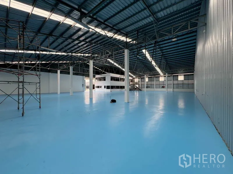 Warehouse for rent in Mueang Pathum Thani, Pathum Thani - Expansive clear-span hall with blue industrial floor coating and high metal roofing.