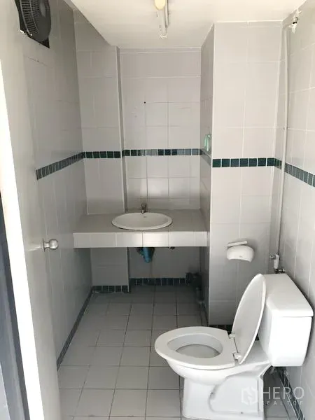 พื้นที่ขายปลีก ให้เช่าในKhlong Toei, Bangkok - ห้องน้ำขนาดกะทัดรัด พร้อมโถสุขภัณฑ์ อ่างล้างมือ ผนังกระเบื้อง และพัดลมระบายอากาศ.