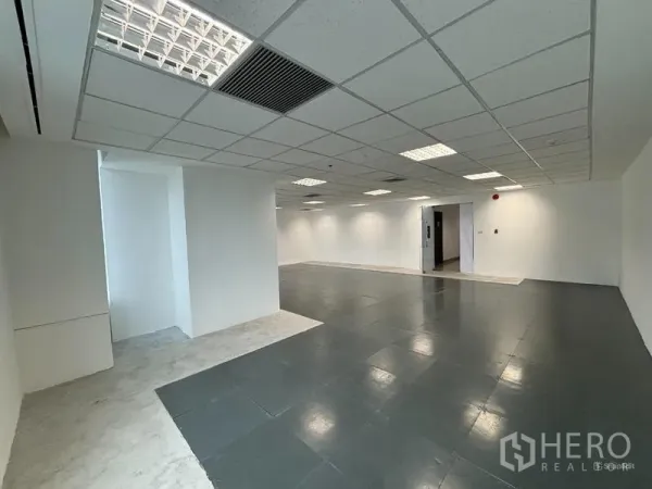 Office Space for rent in Watthana, Bangkok - Spacious office interior featuring raised flooring, air-conditioning vents, recessed lighting, and a doorway to the common corridor.