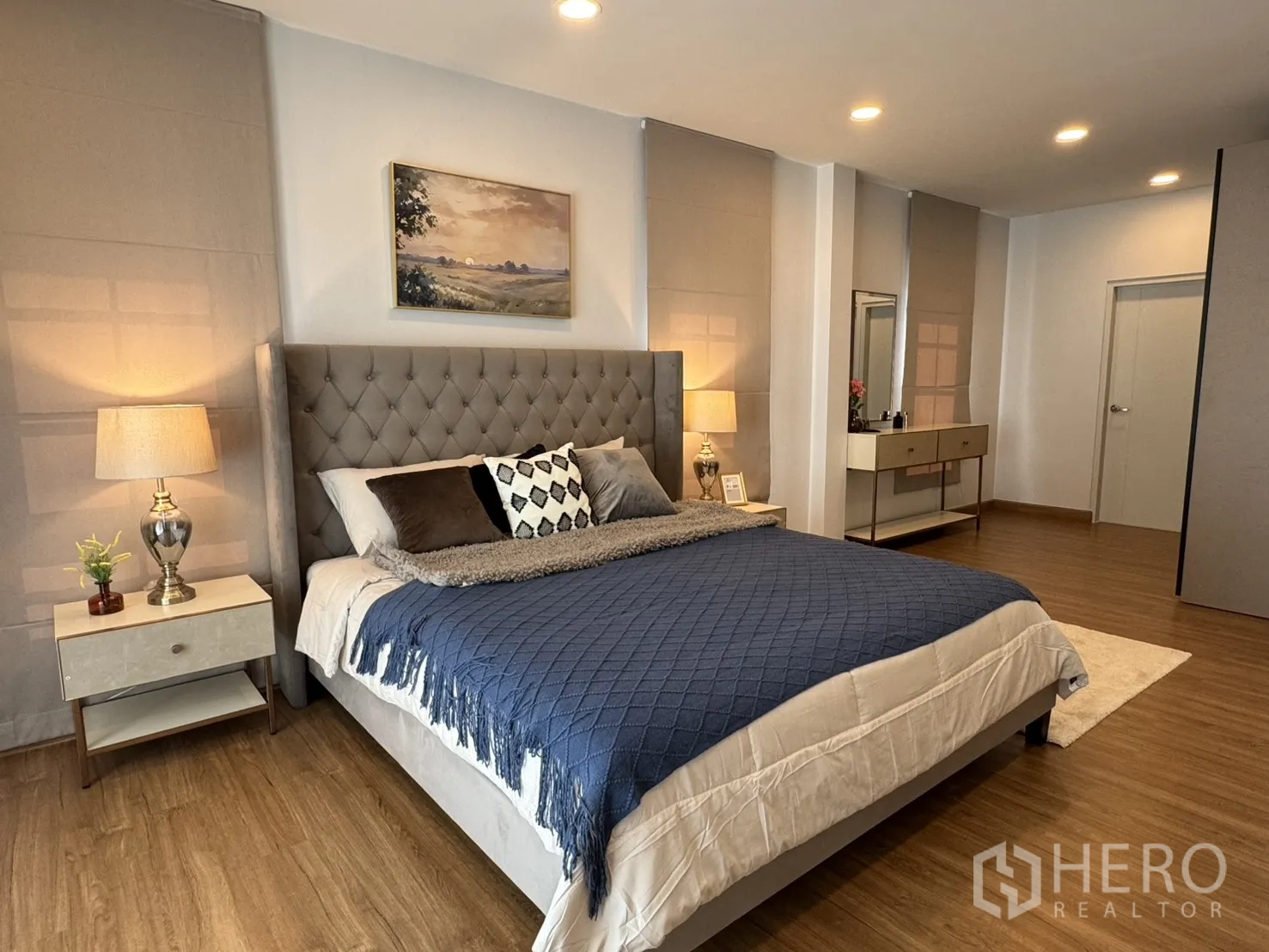 บ้าน for rent in Bang Phli, Samut Prakan - ห้องนอนมาสเตอร์พร้อมหัวเตียงบุผ้า โคมไฟหัวเตียง และพื้นลามิเนตไม้ กว้างโปร่ง