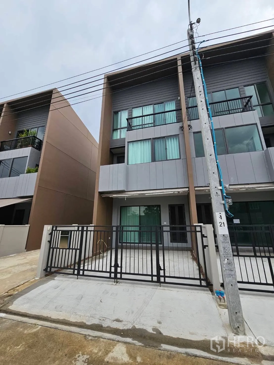 Townhouse for rent in Saphan Sung, Bangkok - Three-storey modern townhouse exterior with small balconies and a gated parking driveway.