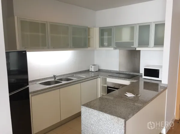 Condominium for rent in Khlong Toei, Bangkok - Modern U-shaped kitchen with granite countertops, ample cabinets and built-in appliances.
