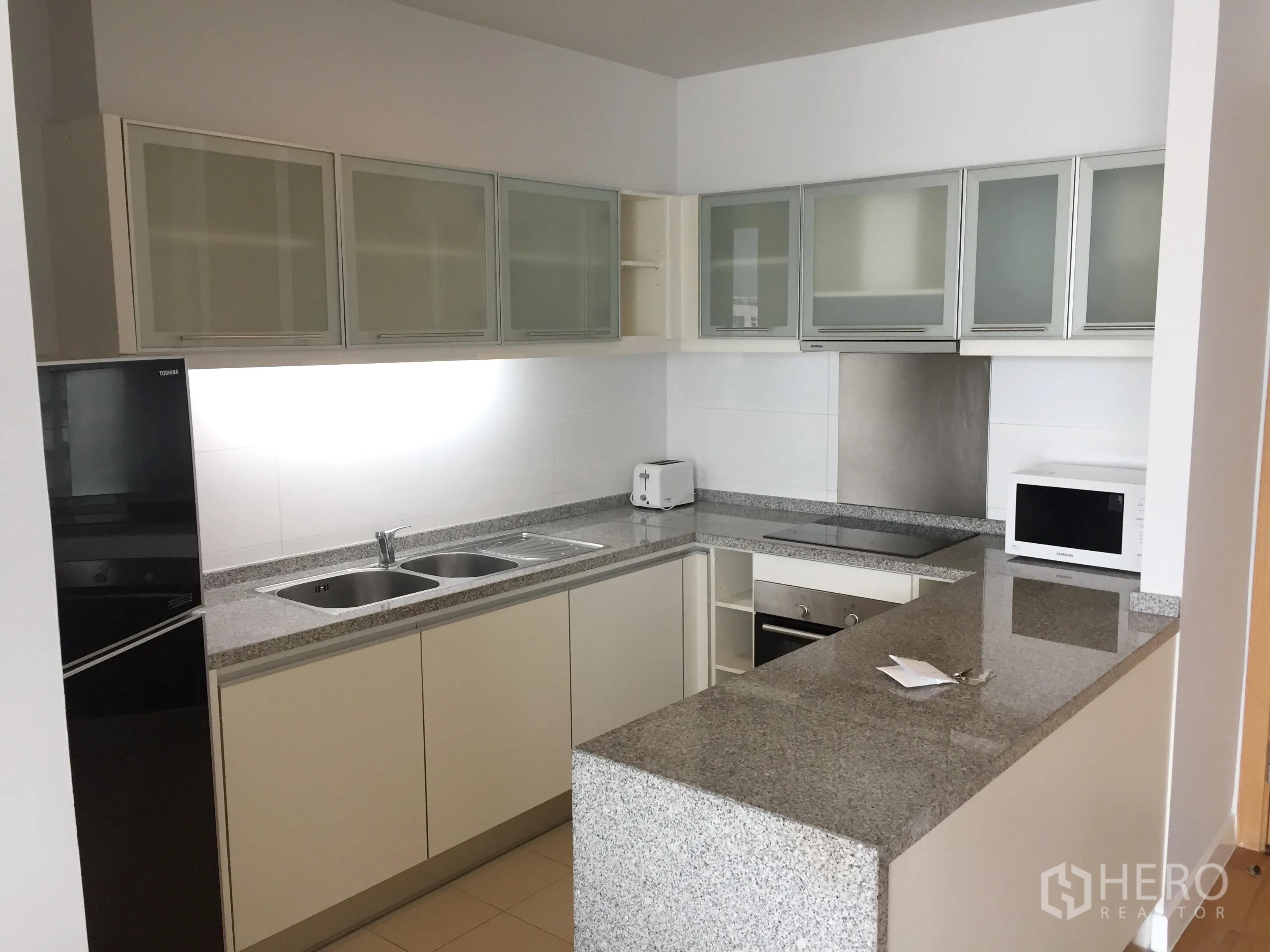 Condominium for rent in Khlong Toei, Bangkok - Modern U-shaped kitchen with granite countertops, ample cabinets and built-in appliances.